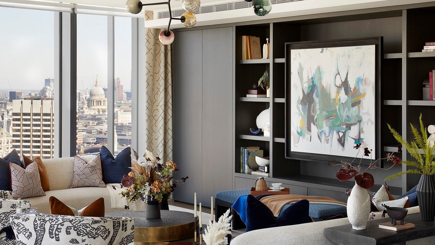 A modern, built-in shelving unit displays books, artwork, and decorative objects within a luxurious living room overlooking a cityscape.